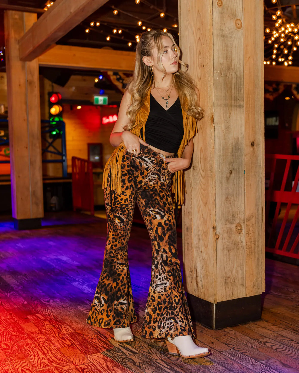 model, madeleine wearing a size 8 ariat greeley boots in daisy's saloon, full outfit by wrangler x lainey wilson, fringe vest, pants