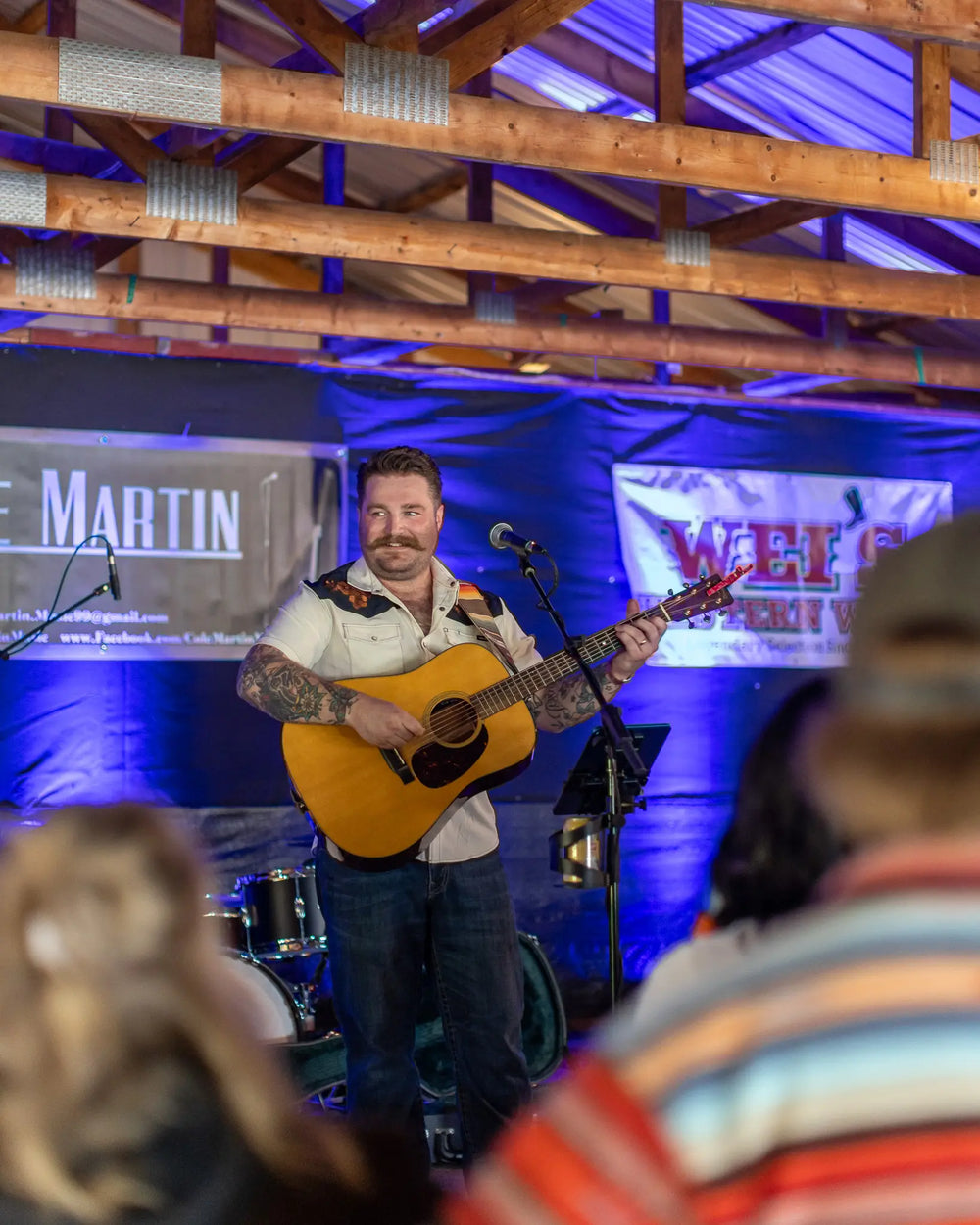 Cole Martin wearing a western Cinch short-sleeve shirt paired with dark Wrangler jeans, posing casually with hands in pockets.